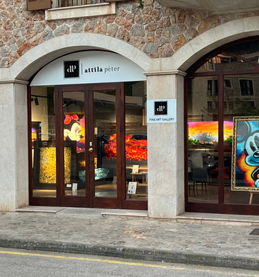 Storefront with art displayed in windows on a stone building
